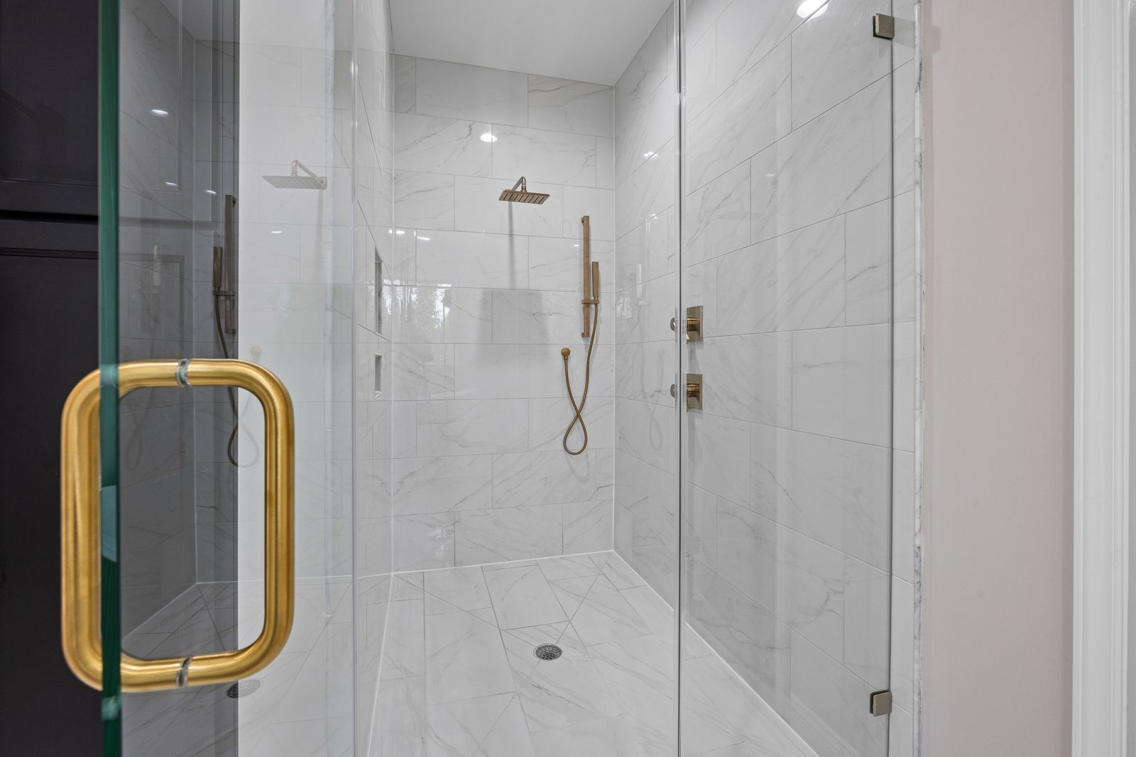 Walk-in shower with frameless custom glass, tiled walls and a built-in niche