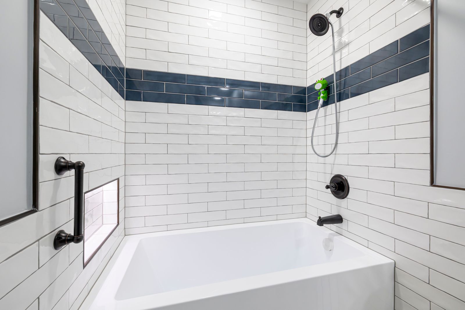 Tiled tub and shower with a grab bar finished to match the fittings