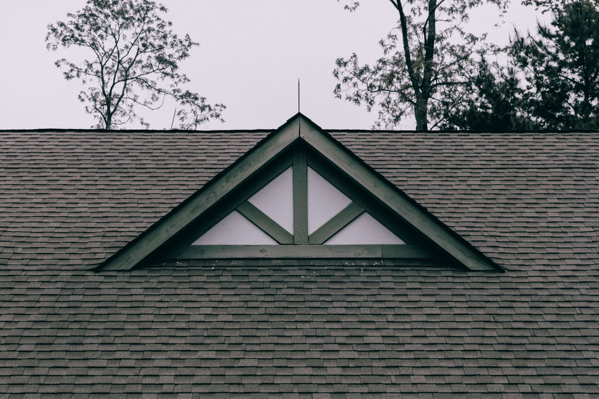 Architectural asphalt shingle roof with a gable vent, seen close against the sky